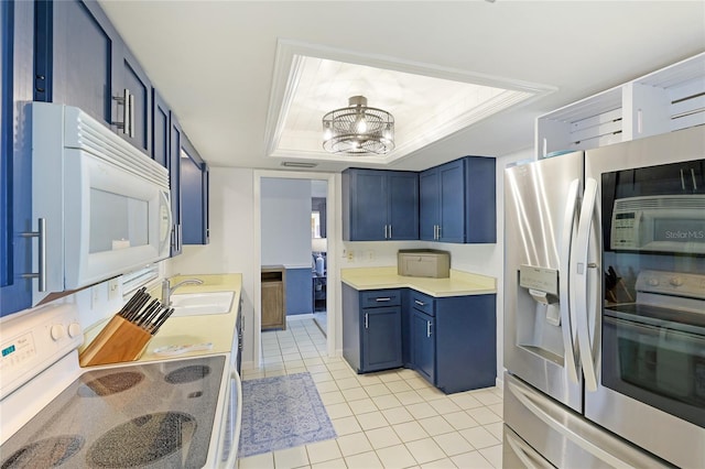 kitchen with light tile patterned floors, a notable chandelier, a tray ceiling, and stainless steel appliances