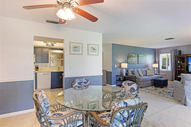 dining area featuring ceiling fan, sink, and light carpet