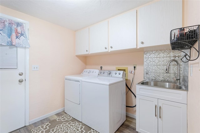 laundry room with light hardwood / wood-style floors, sink, washing machine and clothes dryer, and cabinets