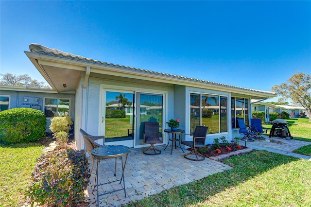 rear view of property with a lawn and a patio