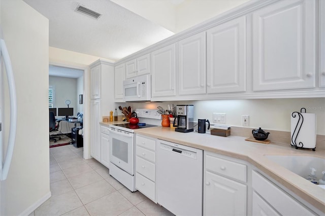 kitchen with light tile floors, white appliances, and white cabinetry