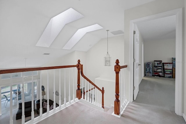 corridor featuring vaulted ceiling with skylight and light colored carpet