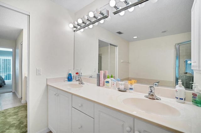 bathroom with double sink, a textured ceiling, and vanity with extensive cabinet space