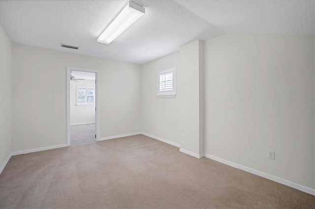 carpeted empty room with ceiling fan and a textured ceiling