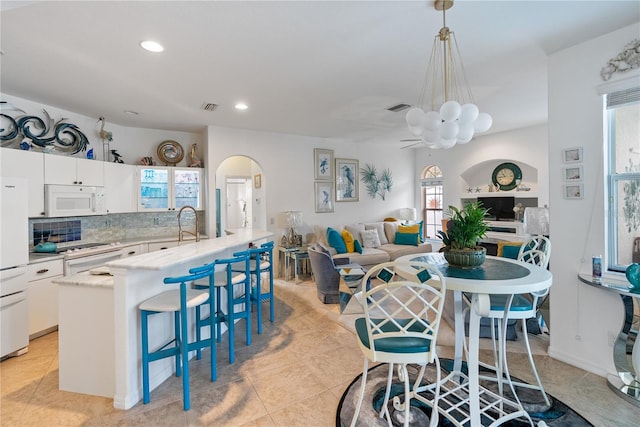 kitchen with arched walkways, white appliances, visible vents, and white cabinets