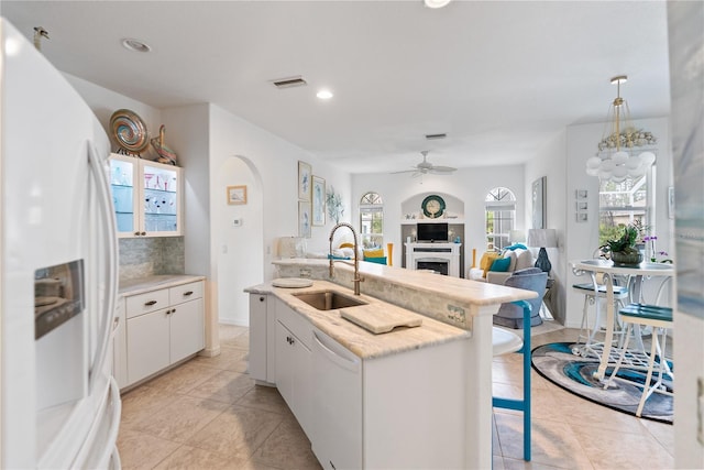 kitchen featuring white appliances, visible vents, a breakfast bar, a fireplace, and a sink