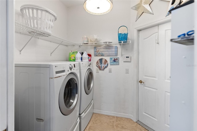 laundry area with laundry area, separate washer and dryer, light tile patterned flooring, and baseboards