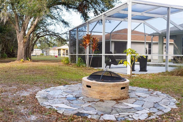 view of yard featuring glass enclosure, a fire pit, and a patio