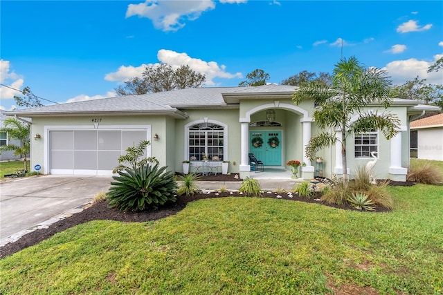 view of front of property with a garage, driveway, a front lawn, and stucco siding