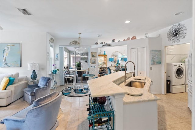 living area featuring light tile patterned floors, washer / clothes dryer, a chandelier, and visible vents