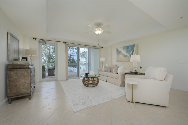 tiled living room with a raised ceiling and ceiling fan