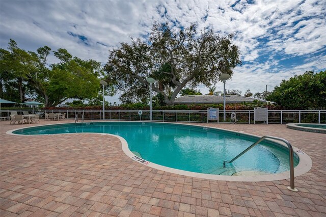 view of swimming pool featuring a hot tub and a patio