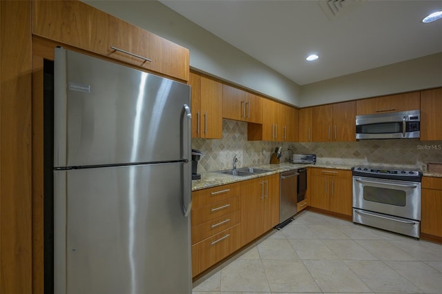 kitchen with sink, light tile patterned floors, stainless steel appliances, light stone countertops, and decorative backsplash