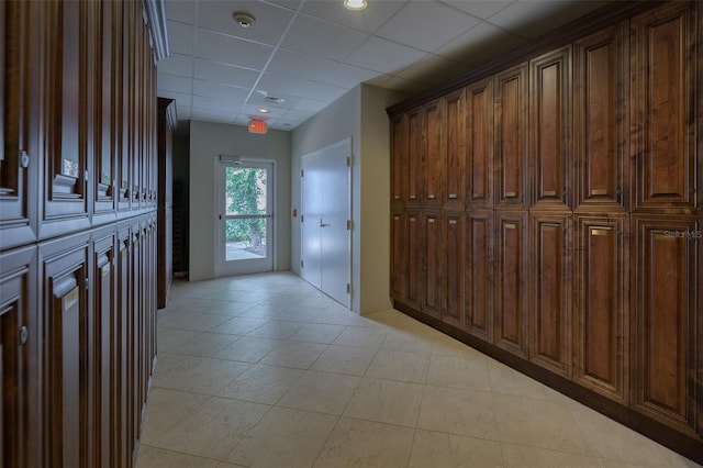 hall with a paneled ceiling and light tile patterned floors