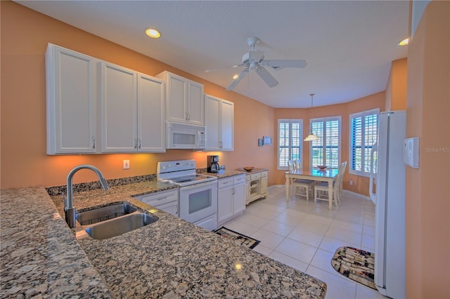 kitchen with dark stone countertops, white appliances, white cabinets, and sink