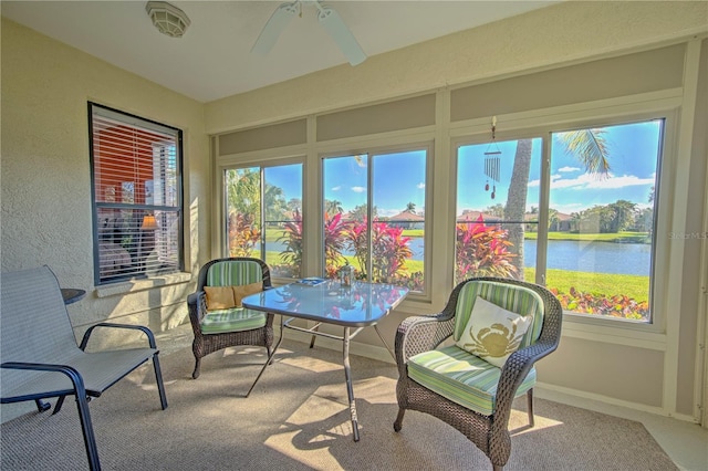 sunroom / solarium with ceiling fan and a water view