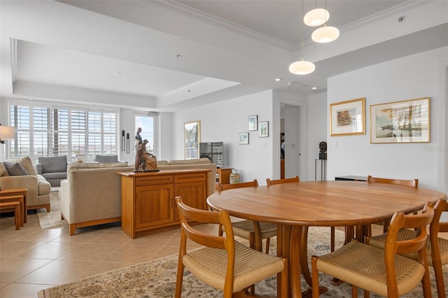 dining space featuring a raised ceiling, ornamental molding, and light tile patterned floors