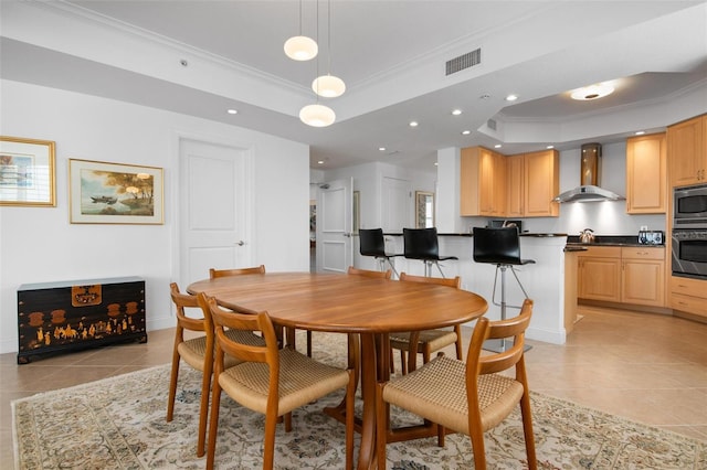 dining area with light tile patterned flooring, crown molding, and a tray ceiling