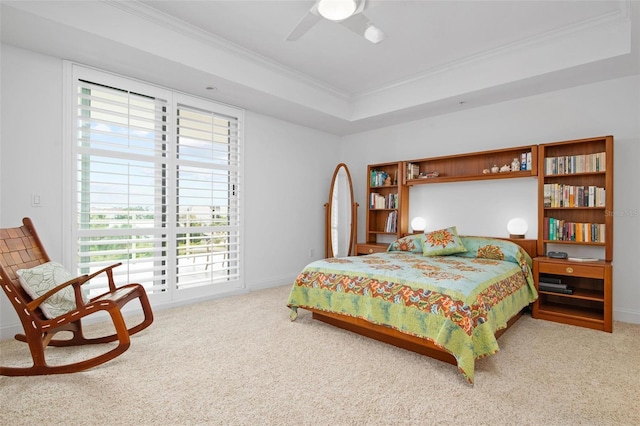 carpeted bedroom with ornamental molding, ceiling fan, and a tray ceiling