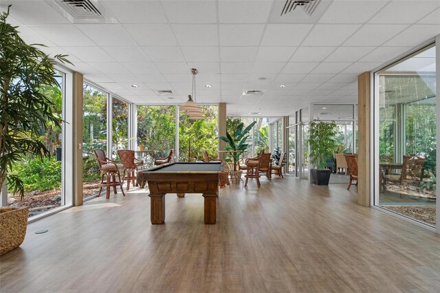 rec room with a drop ceiling, a wall of windows, billiards, and wood-type flooring