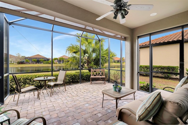 sunroom with ceiling fan and a water view