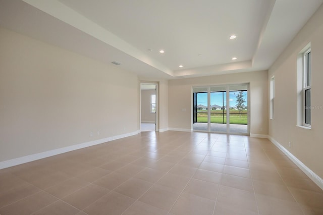 tiled empty room featuring a tray ceiling