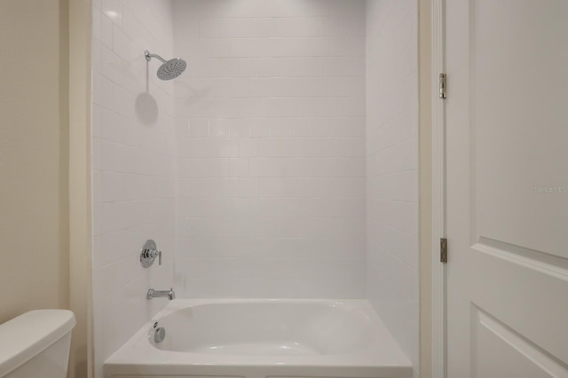 bathroom featuring toilet and tiled shower / bath