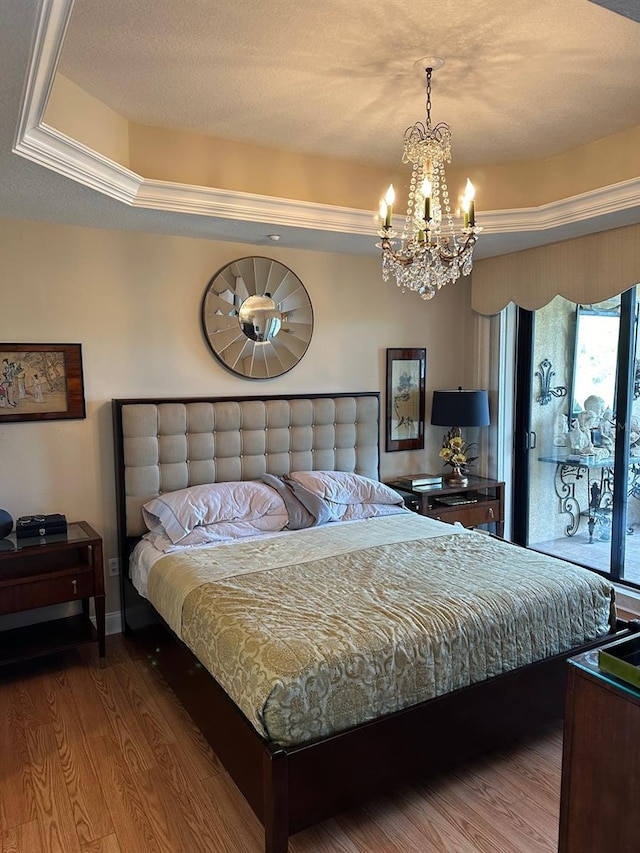 bedroom with a tray ceiling, dark hardwood / wood-style flooring, and a chandelier