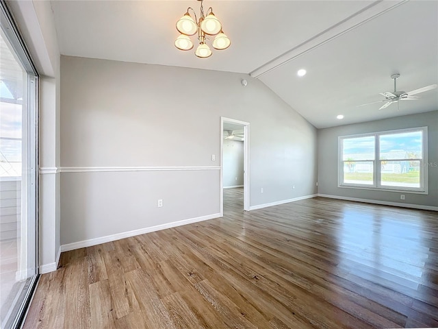 spare room featuring vaulted ceiling, hardwood / wood-style flooring, and ceiling fan with notable chandelier