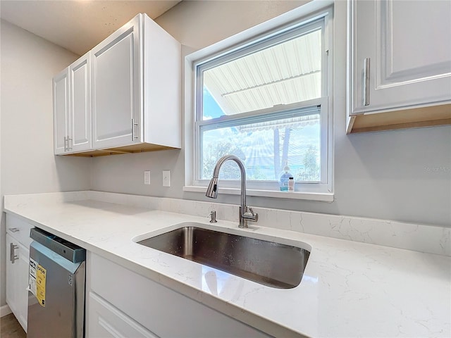 kitchen featuring dishwasher, white cabinetry, sink, and light stone countertops