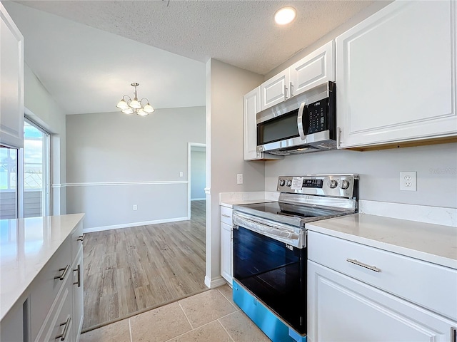 kitchen featuring white cabinetry, appliances with stainless steel finishes, light wood-type flooring, a chandelier, and vaulted ceiling