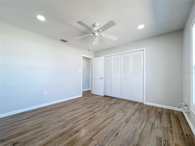 unfurnished bedroom with ceiling fan, a closet, a textured ceiling, and wood-type flooring