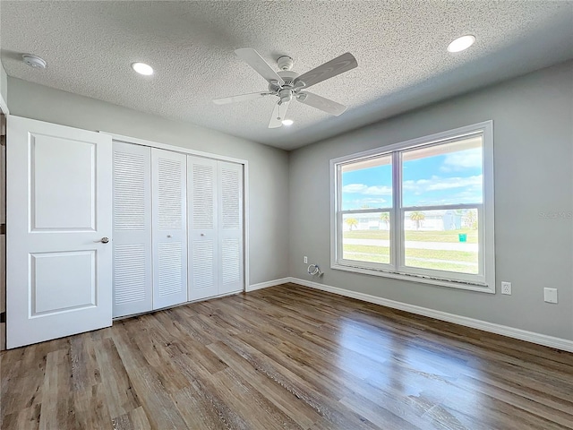 unfurnished bedroom featuring a closet, a textured ceiling, ceiling fan, and hardwood / wood-style flooring