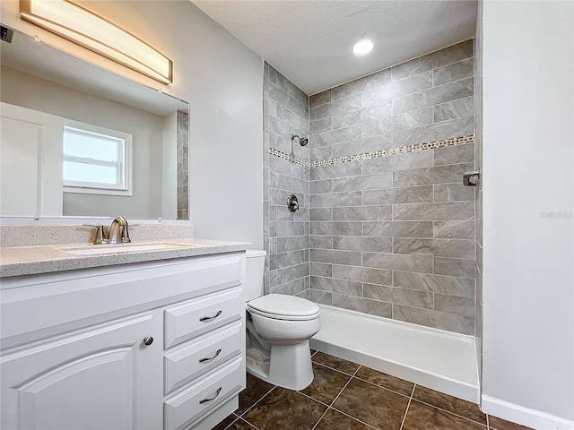 full bathroom featuring tiled shower / bath combo, toilet, vanity with extensive cabinet space, tile floors, and a textured ceiling