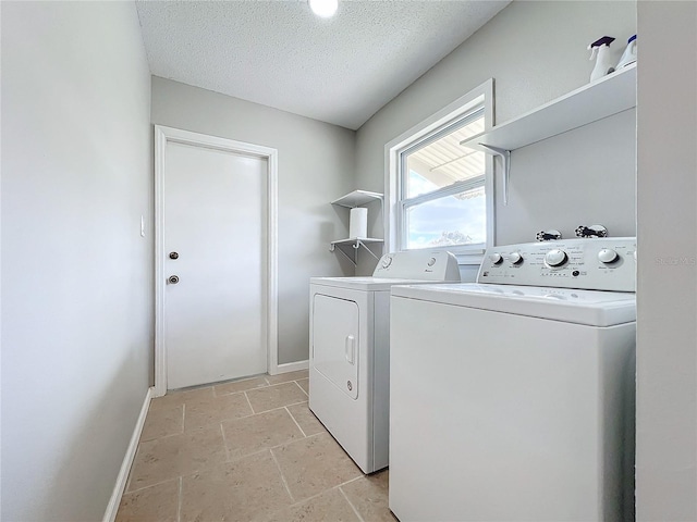 laundry area featuring washing machine and clothes dryer, light tile flooring, and a textured ceiling