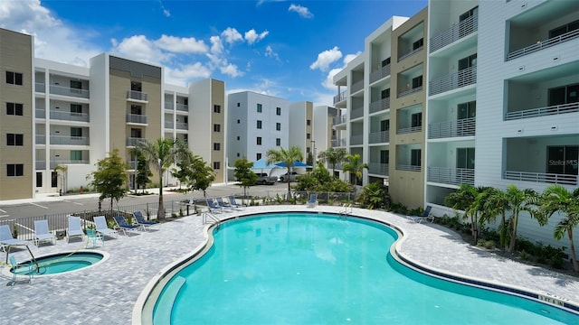 community pool featuring a patio area, fence, and a hot tub