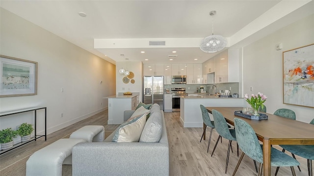 living area with a chandelier, recessed lighting, visible vents, baseboards, and light wood-type flooring