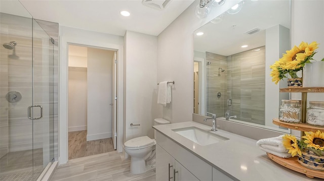 bathroom with wood-type flooring, an enclosed shower, vanity, and toilet