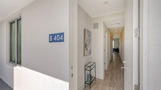 corridor featuring light wood-type flooring, baseboards, and visible vents