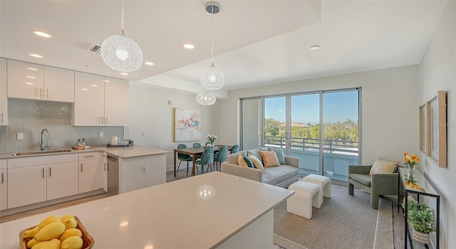 kitchen with sink, decorative light fixtures, tasteful backsplash, a raised ceiling, and white cabinets