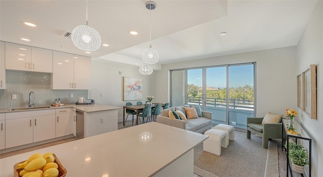 kitchen featuring a sink, white cabinetry, open floor plan, light countertops, and hanging light fixtures