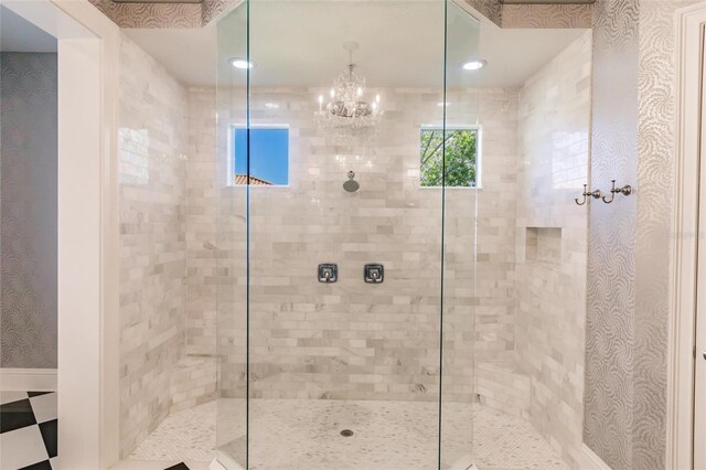 bathroom with tiled shower and an inviting chandelier