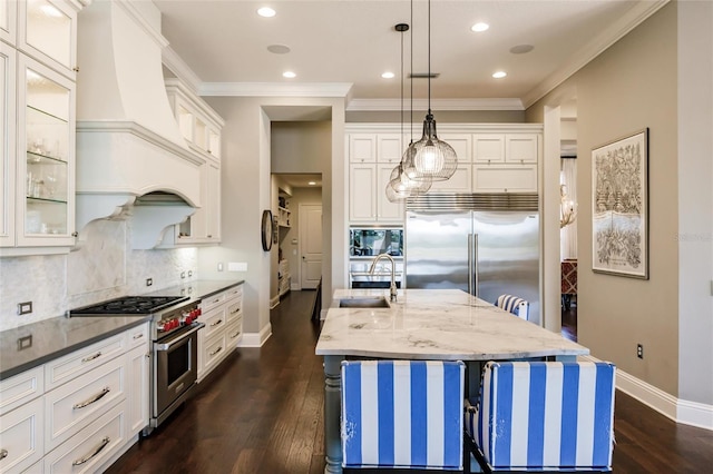 kitchen with custom exhaust hood, dark wood-type flooring, sink, pendant lighting, and high quality appliances