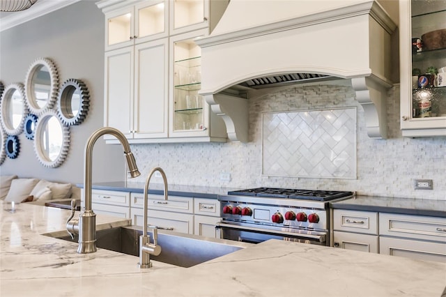 kitchen with decorative backsplash, crown molding, custom range hood, and high end stainless steel range oven