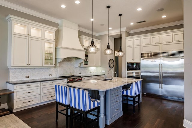 kitchen featuring built in appliances, custom range hood, hanging light fixtures, and dark wood-type flooring