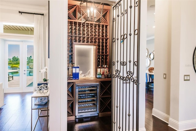 wine area featuring wine cooler, crown molding, beamed ceiling, and dark wood-type flooring