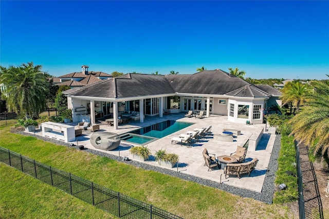 back of house with french doors, an outdoor living space with a fire pit, a pool with hot tub, a patio, and a lawn