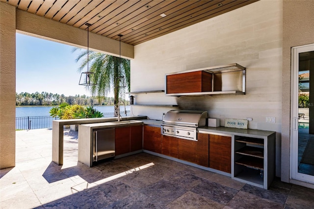 view of patio / terrace featuring sink, a water view, area for grilling, and exterior kitchen