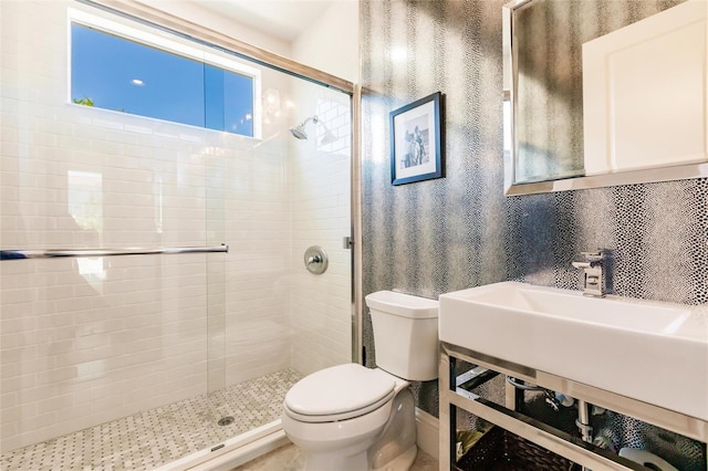 bathroom featuring toilet, a shower with shower door, and sink