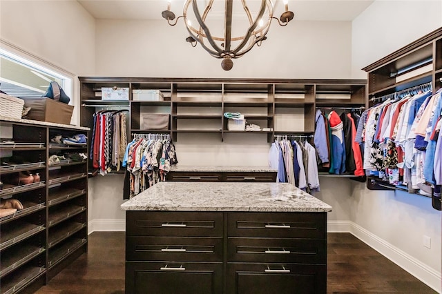 walk in closet with a notable chandelier and dark hardwood / wood-style flooring